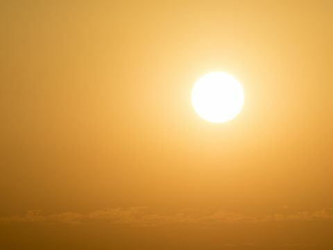 Пълен кадър светещо слънце по залез слънце с оранжево и жълто небе