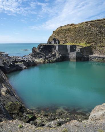 добре известна характеристика в националния парк Pembrokeshire крайбрежие стара кариера, наводнена от морето, за да създаде дълбоко син басейн останки от стари сгради край водата