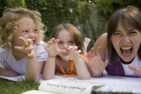 жена и две момичета ръмжат и вдигат ръце като нокти, докато лежат в задния двор