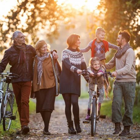 усмихнато семейство от няколко поколения, което се разхожда с велосипеди сред природата и се наслаждава на времето си заедно