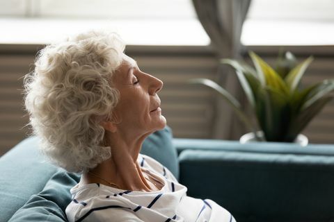 страничен изглед отблизо лице на 60-те години зряла спокойна жена затворени очи наслаждавайте се на чист въздух прекарвайте време у дома облегнати на дивана, почивайки набирайки умствена и физическа сила внимание медитация за възрастни концепция