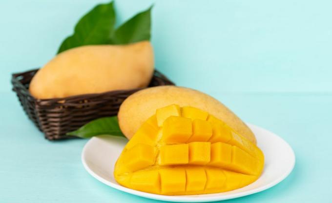Едър план на плод манго в чиния на син фон
