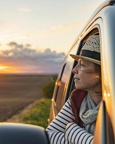 жена на 40 години се наслаждава на гледката към провинцията от своя кемпер тя изглежда доволна и спокойна