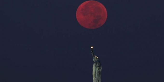 пълната луна залязва зад статуята на свободата в Ню Йорк